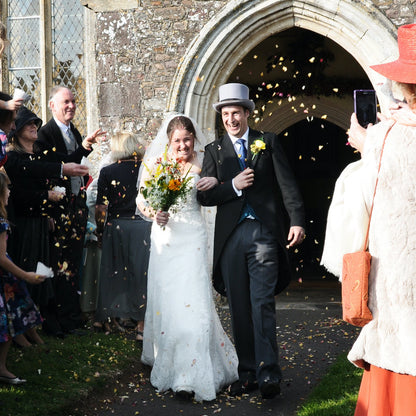 Wedding couple exiting church with guests throwing confetti.