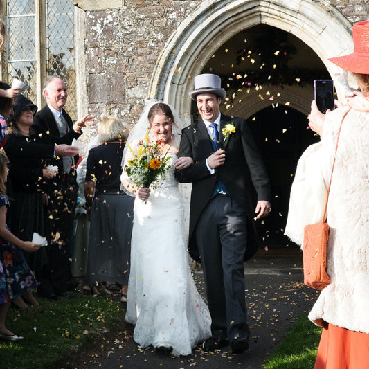 Wedding couple exiting church with guests throwing confetti.